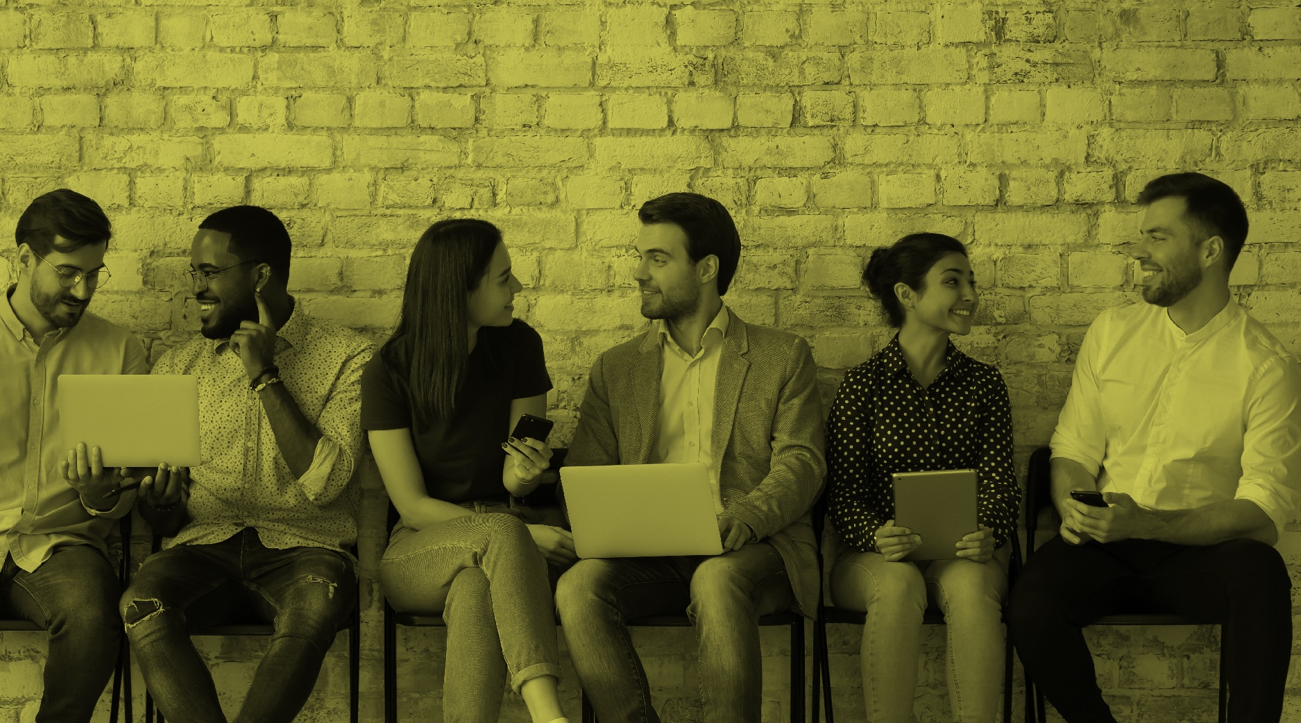 Professionals sitting in a row talking and looking at computers